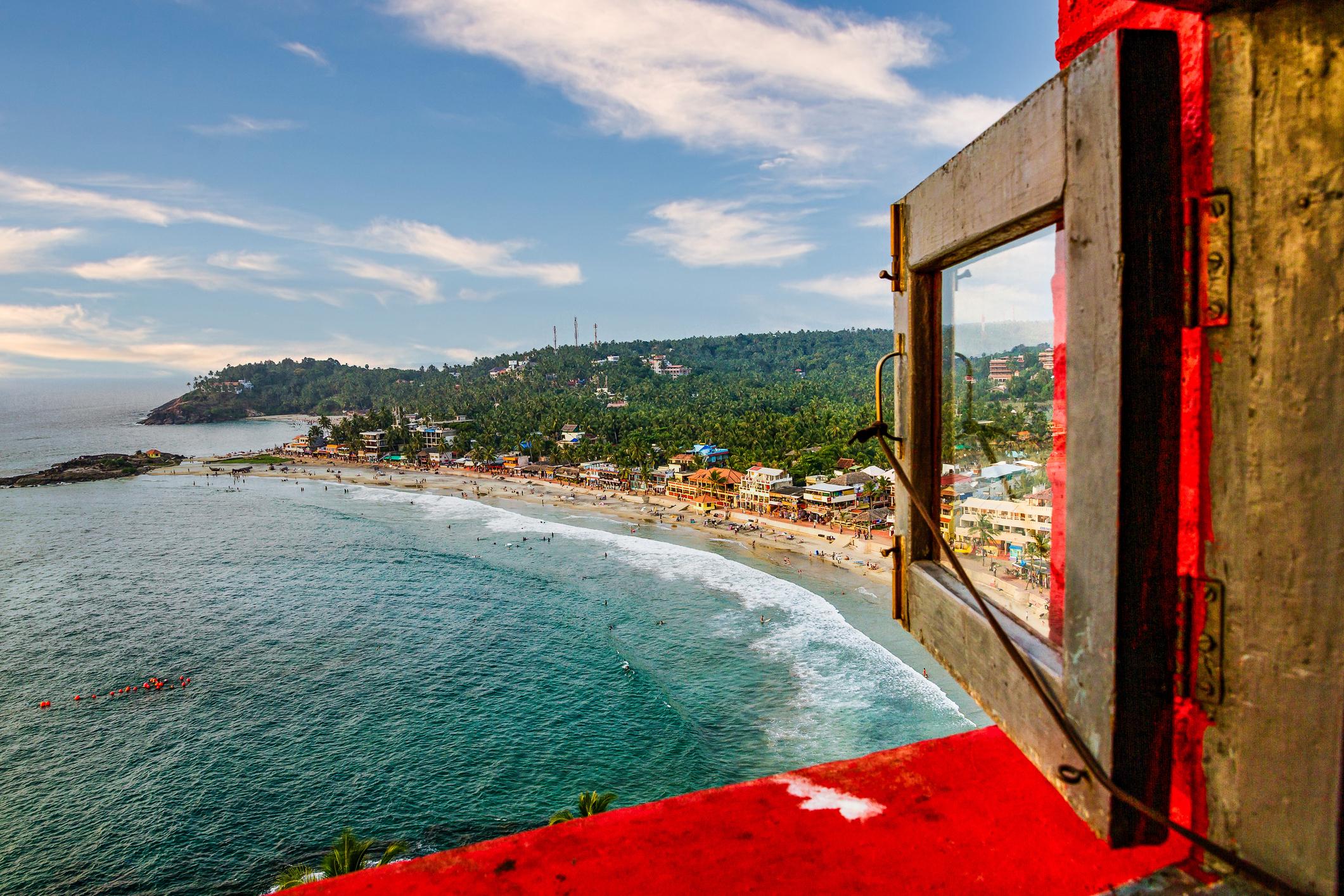 Panoramic view of Kovalam's crescent beach with palm trees and golden sand